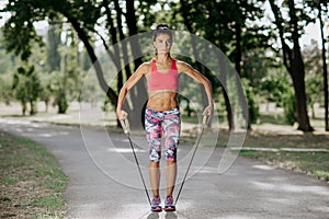 Female athlete exercising with resistance band in the park. Tough woman using a resistance band in her exercise routine.