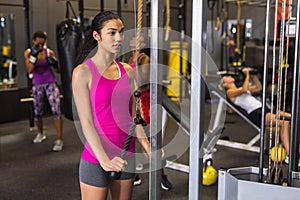 Female athlete exercising with triceps pushdown machine in fitness center