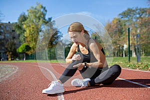 Female athlete experiencing painful leg injury while running on a sunny track
