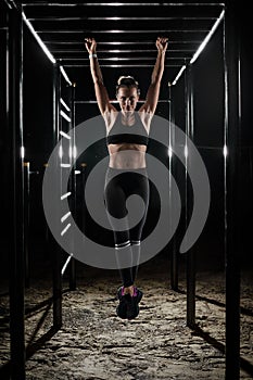 Female athlete with fit body hanging on the pullup bar