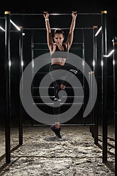 Female athlete with fit body hanging on the pullup bar