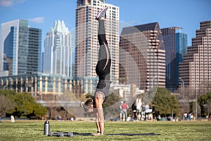 Female athlete and fitness trainer balancing in handstand outdoors in urban city park