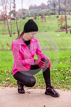 Female athlete hurting from a knee injury on a cold winter day on the training track of an urban park.