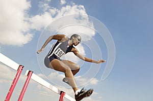 Female Athlete Jumping Hurdle