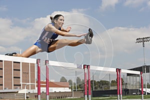 Female Athlete Jumping Over A Hurdles