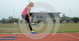 Female athlete jumping over hurdles on a running track 4k