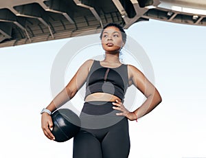 Female athlete with medicine ball outdoors looking away