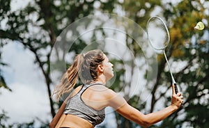 Female Athlete Playing Badminton in a Park on a Sunny Day, Enjoying Her Workout Outdoors.