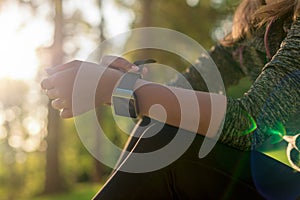 Female athlete putting on her her smart watch to monitor workout performance. Lifestyle wearable technology concept.