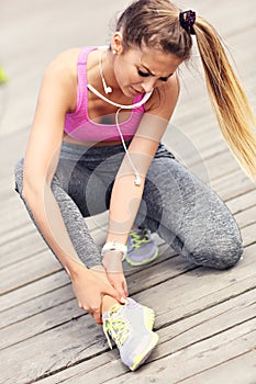 Female athlete runner touching foot in pain outdoors