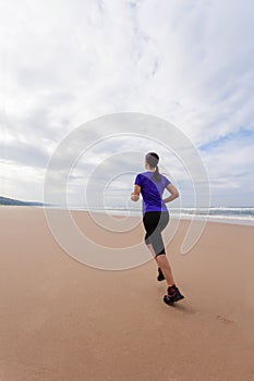 Female athlete running at the beach on a Fall day