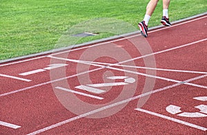 Female athlete running over the lines of a stadium track.