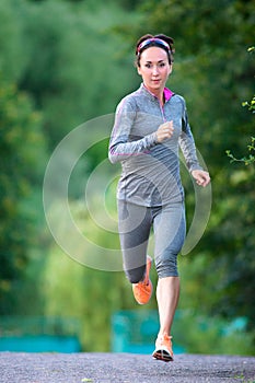 Female Athlete runs approaching at city park. Running woman outd