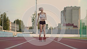 Female athlete starting her sprint on a running track. Runner taking off from the starting blocks on running track