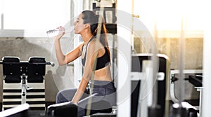 Female athlete taking rest and drinking woter after exercising at gym. Fitness Healthy lifestye and workout at gym concept photo
