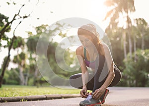 Female athlete tying laces for jogging on road Runner getting ready for training. Sport lifestyle