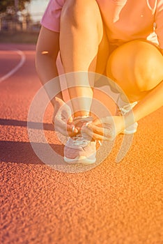 Female athlete tying laces for jogging , sunset