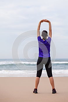 Female athlete warming up and stretching the upper body before running