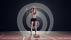 Female athletes warming up at running track before a race. In slow motion. Woman runner at athletics track crouching at