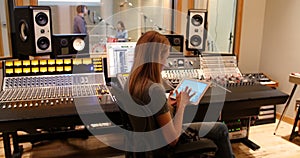 Female audio engineer using sound mixer using digital tablet