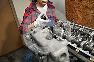 Female auto mechanic fixing car engine at service station