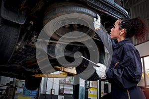 Female auto mechanic work in garage, car service technician woman check and repair customer car at automobile service center,