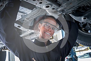 Female auto mechanic work in garage, car service technician woman check and repair customer car at automobile service center,