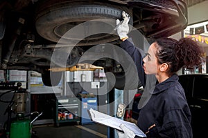 Female auto mechanic work in garage, car service technician woman check and repair customerâ€™s car at automobile service center,