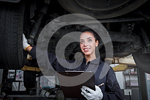 Female auto mechanic work in garage, car service technician woman check and repair customerâ€™s car at automobile service center,