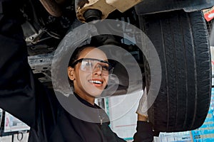 Female auto mechanic workin garage, car service technician woman check and repair customerâ€™s car at automobile service center,