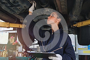 Female auto mechanic working in garage, car service technician woman checking and repairing the customerÃ¢â¬â¢s car at automobile
