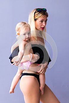 Female with a baby in her arms to frown and laughs against a blue background