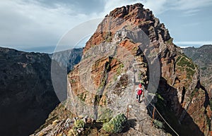 Female backpacker walking by famous mountain footpath from Pico do Arieiro to Pico Ruivo with breathtaking views on Portuguese