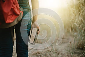 Female backpackers standing and hold the Bible.