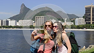 Female backpackers tourists with smartphone in Rio de Janeiro with Christ the Redeemer in background.