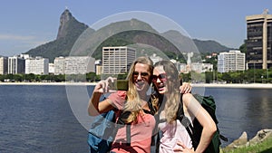 Female backpackers tourists with smartphone in Rio de Janeiro with Christ the Redeemer in background.