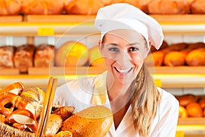 Female baker in bakery selling bread by basket