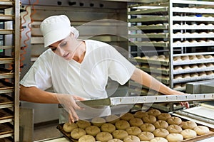 Female baker baking bread rolls