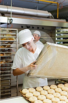 Female baker baking bread rolls