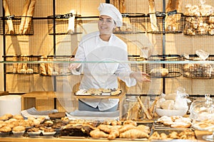 Female baker confidently welcoming customers into her bakery