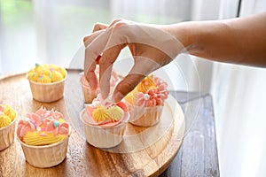 A female baker decorating her beautiful homemade cupcake with tiny white chocolate ball