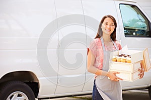 Female Baker Delivering Cakes Standing In Front Of Van