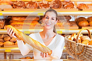 Female baker in her bakery with baguette photo