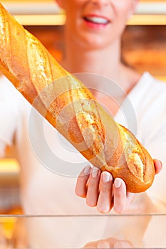 Female baker in her bakery with baguette