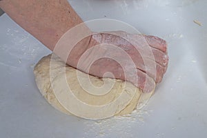 A female baker kneads dough with her hands for modeling dumplings