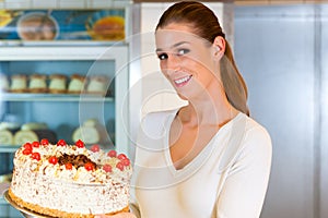 Female baker or pastry chef with torte photo