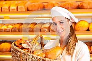 Female baker selling bread by basket in bakery