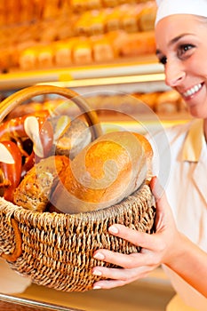 Female baker selling bread by basket in bakery