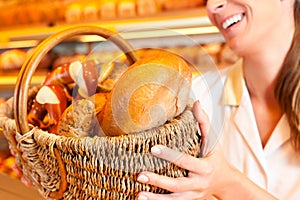 Female baker selling bread by basket in bakery