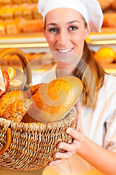 Female baker selling bread by basket in bakery